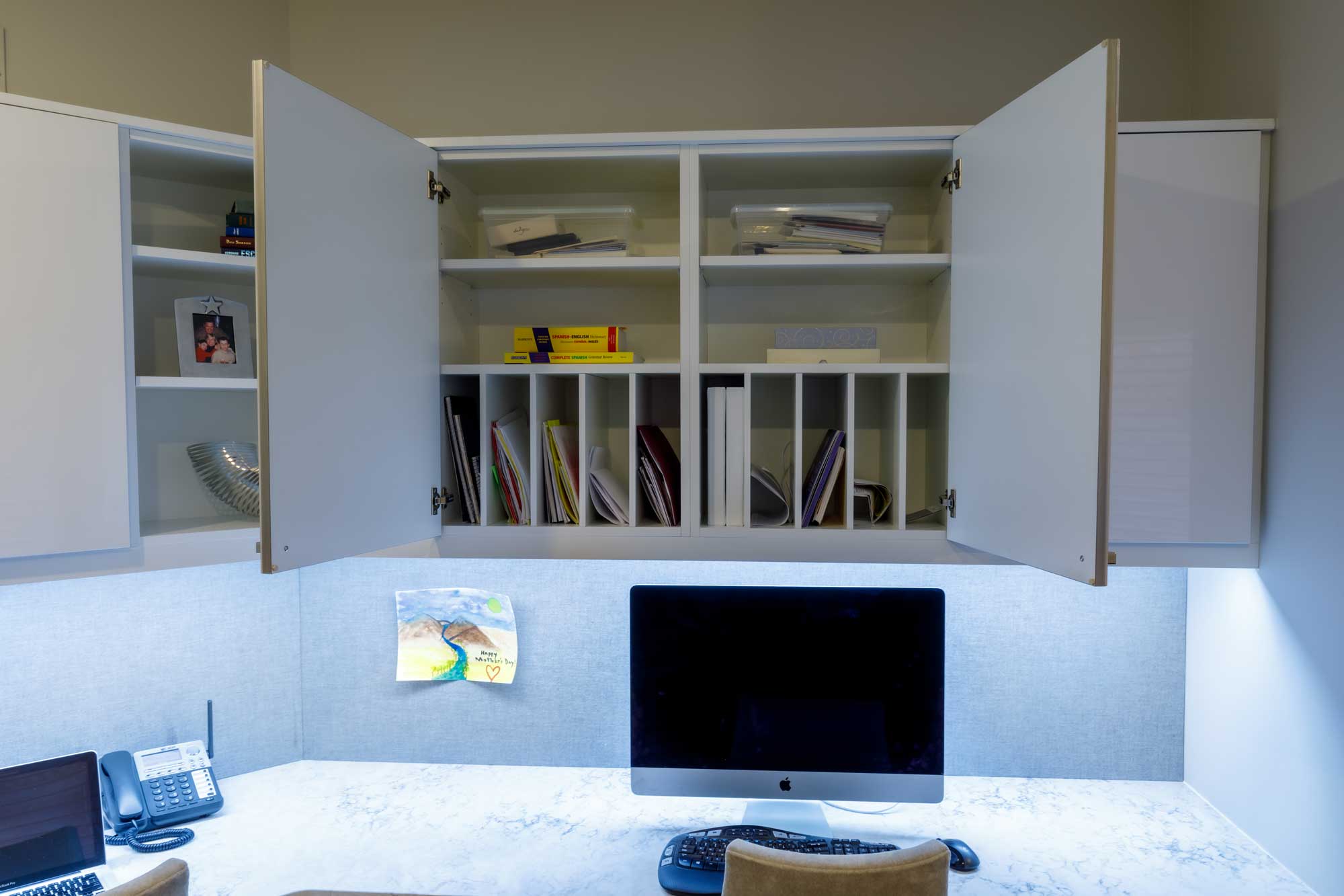 Home office with opened white cabinets above office desk