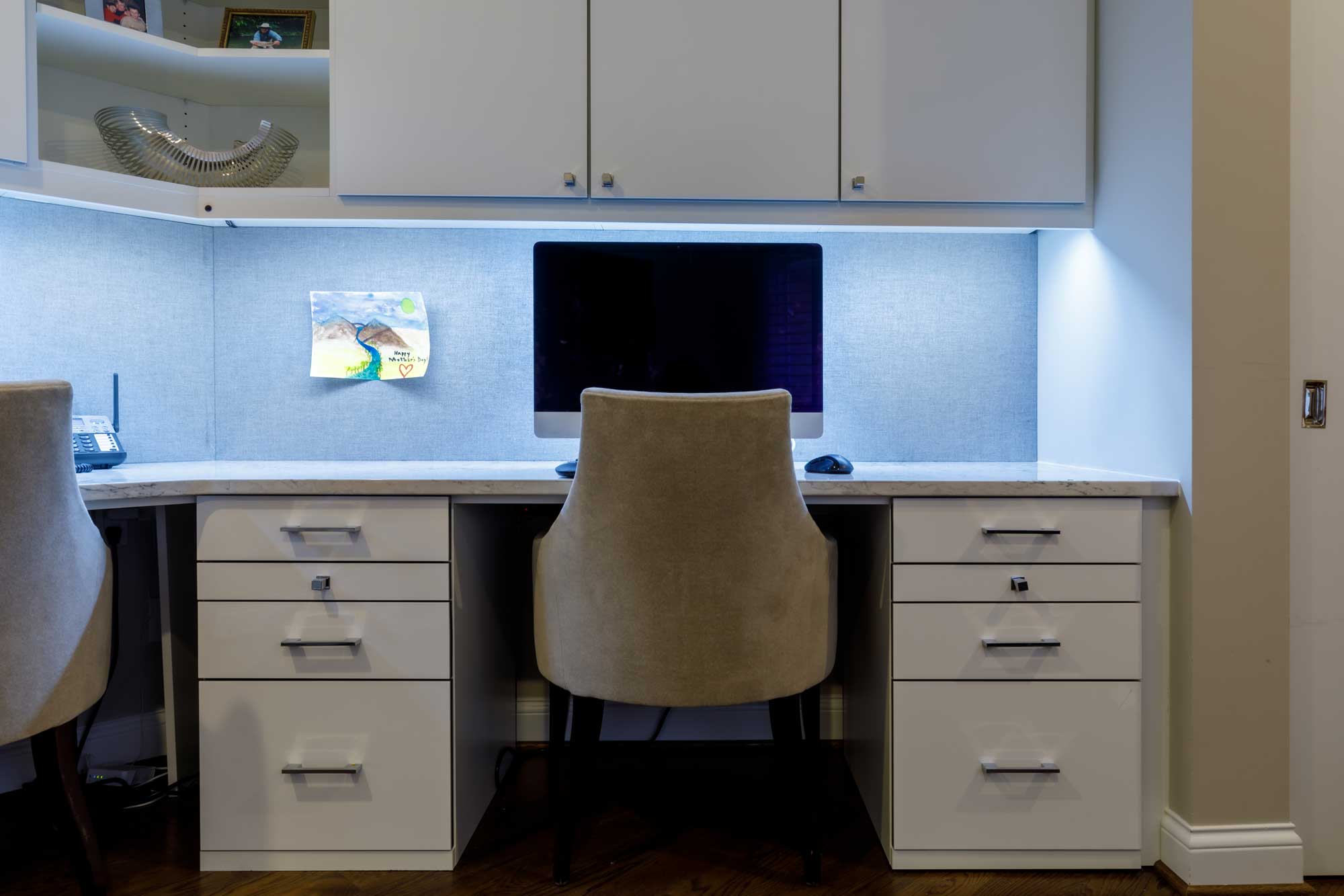 Home office with white cabinets above office desk