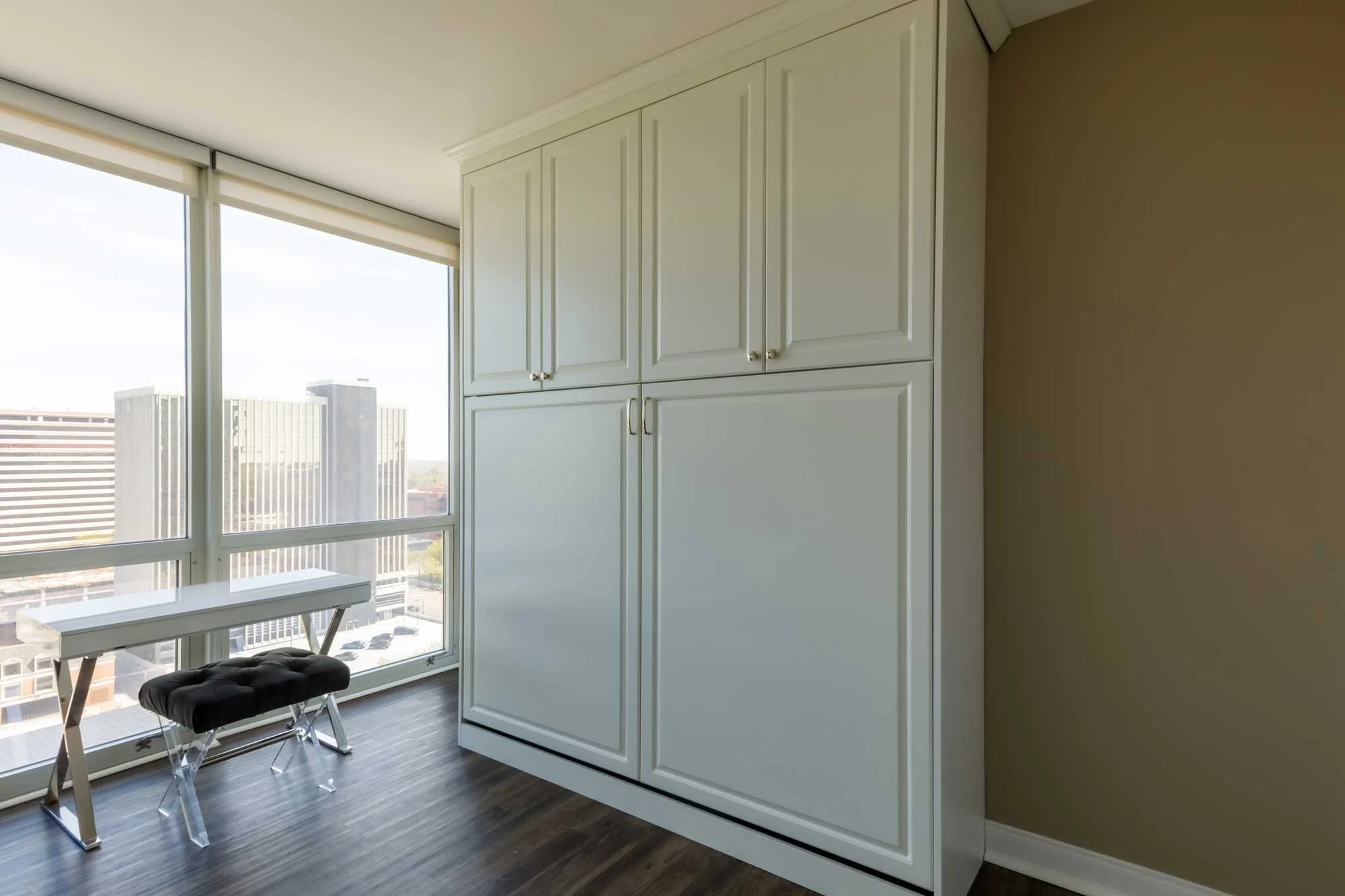 Folded up wall-bed with white overhead cabinets