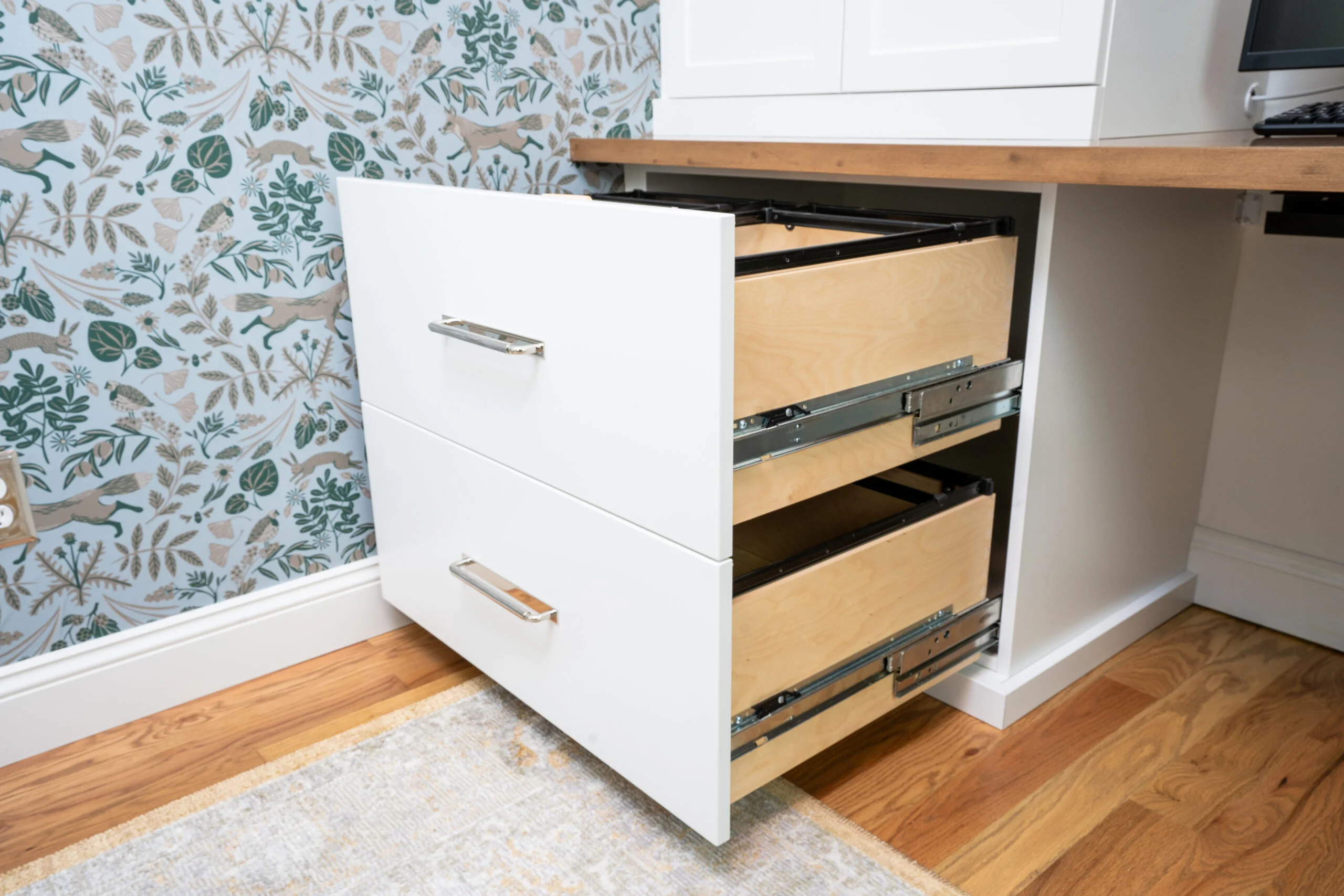 Custom white file cabinet with two open drawers, maple interiors, and modern pulls on wood flooring with a patterned rug.