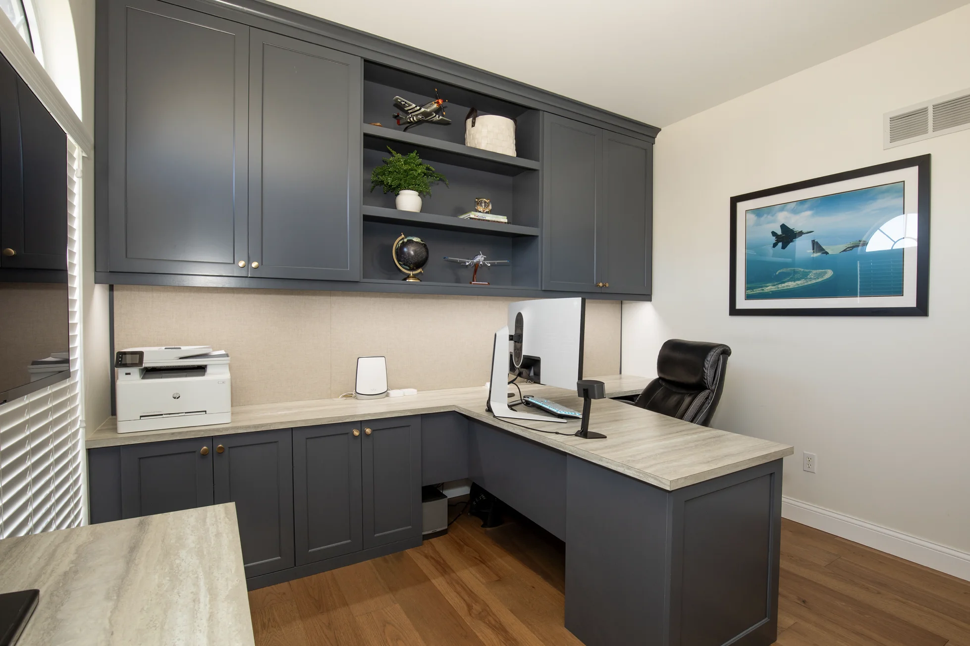 Home office with dark gray custom cabinets, light wood countertops, and a black office chair.